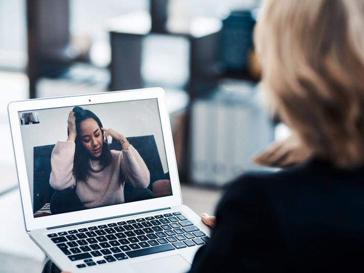 Frau mit blonden Haaren sitzt vor dem Laptop und spricht mit einer anderen Frau über einen Videoanruf