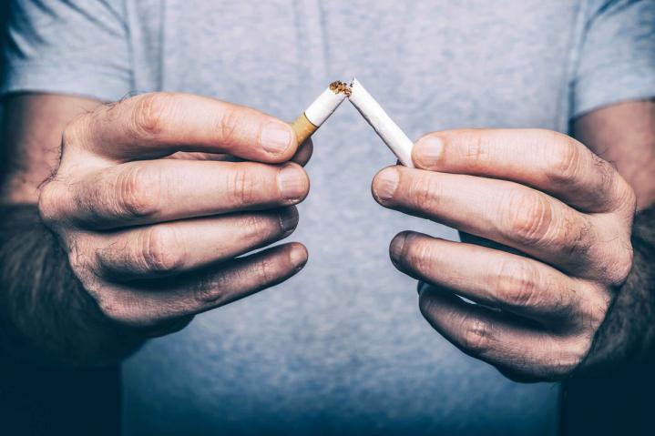 Mann zerbricht symbolisch seine Zigarette, um das Rauchen zu beenden