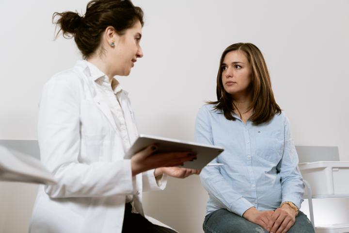 Junge Frau ist beim Arzt und redet mit der Ärztin über ihren Tumor.
