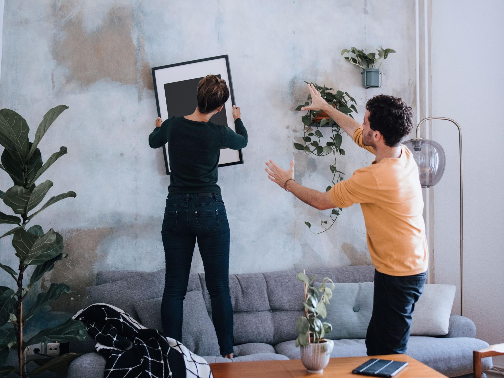 Junges Paar hängt Bild an die Wand in der neuen Wohnung
