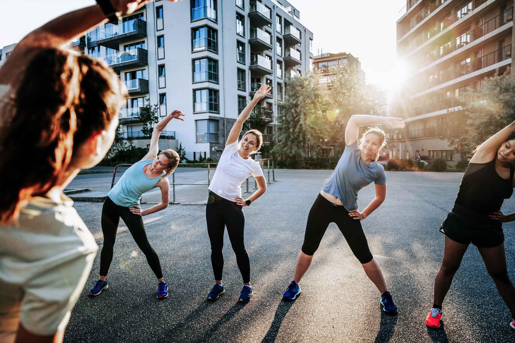 In einer urbanen Umgebung treiben 4 junge Frauen Sport. Die Sonne scheint.